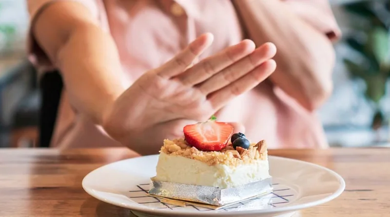 Woman refusing a sugary dessert, illustrating cravings control